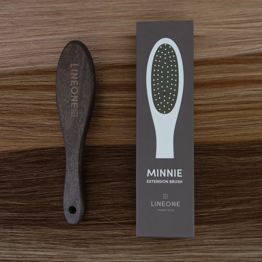 LINEONE Hair MINNIE Extension Brush with dark wood handle next to its packaging box on blonde hair