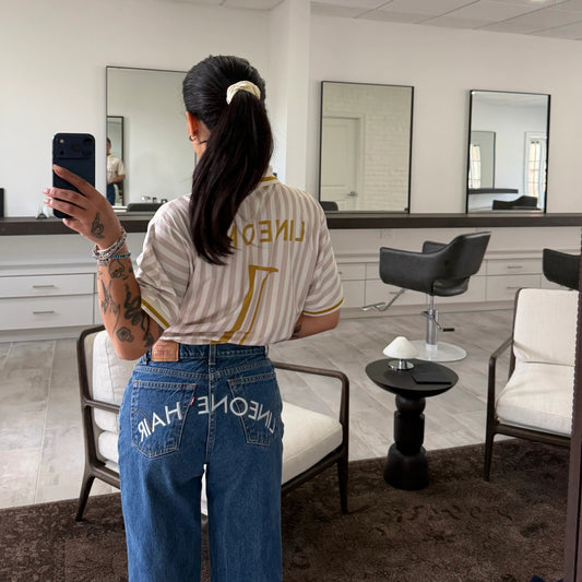 Mirror selfie of stylist in LINEONE Hair Jeans with embroidered back-pocket wordmark and away jersey