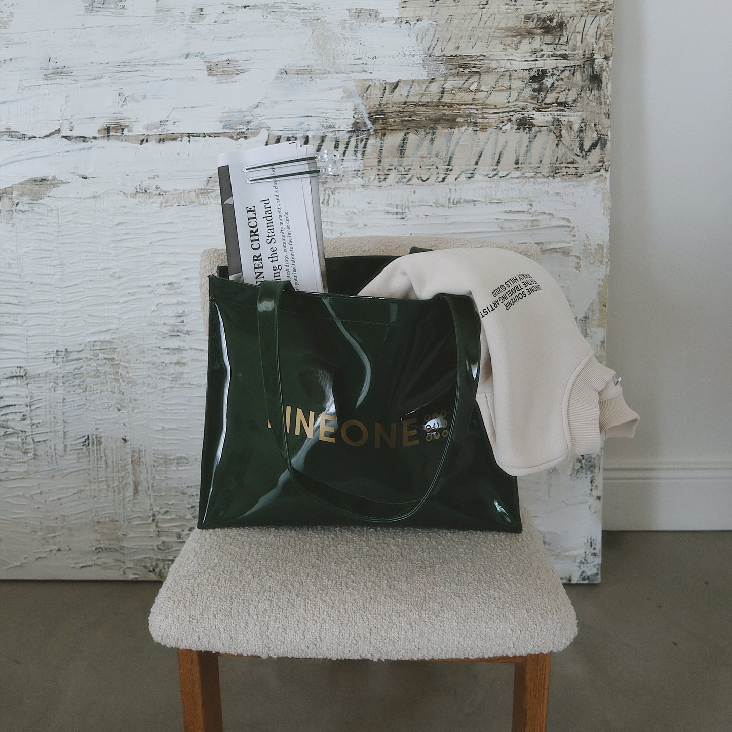 LINEONE Hair Rodeo Bag on a boucle stool with Newsprint and a folded ivory sweatshirt beside textured art