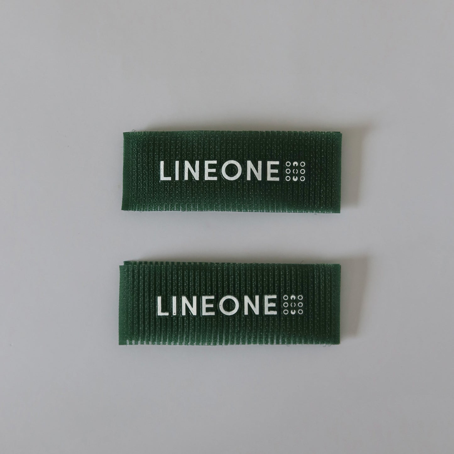 Pair of LINEONE Hair Grippers in hunter green velcro stacked parallel on light grey background