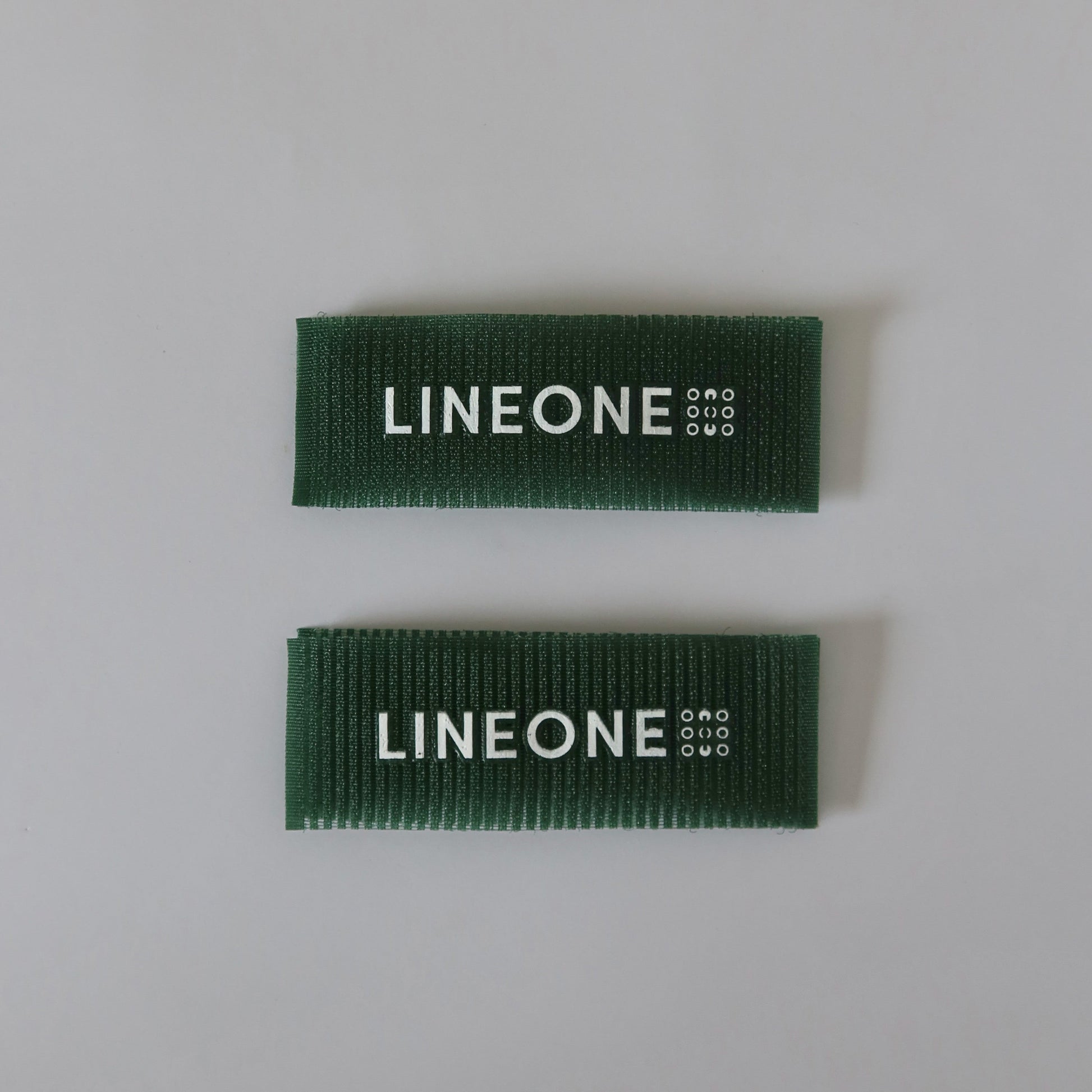 Pair of LINEONE Hair Grippers in hunter green velcro stacked parallel on light grey background