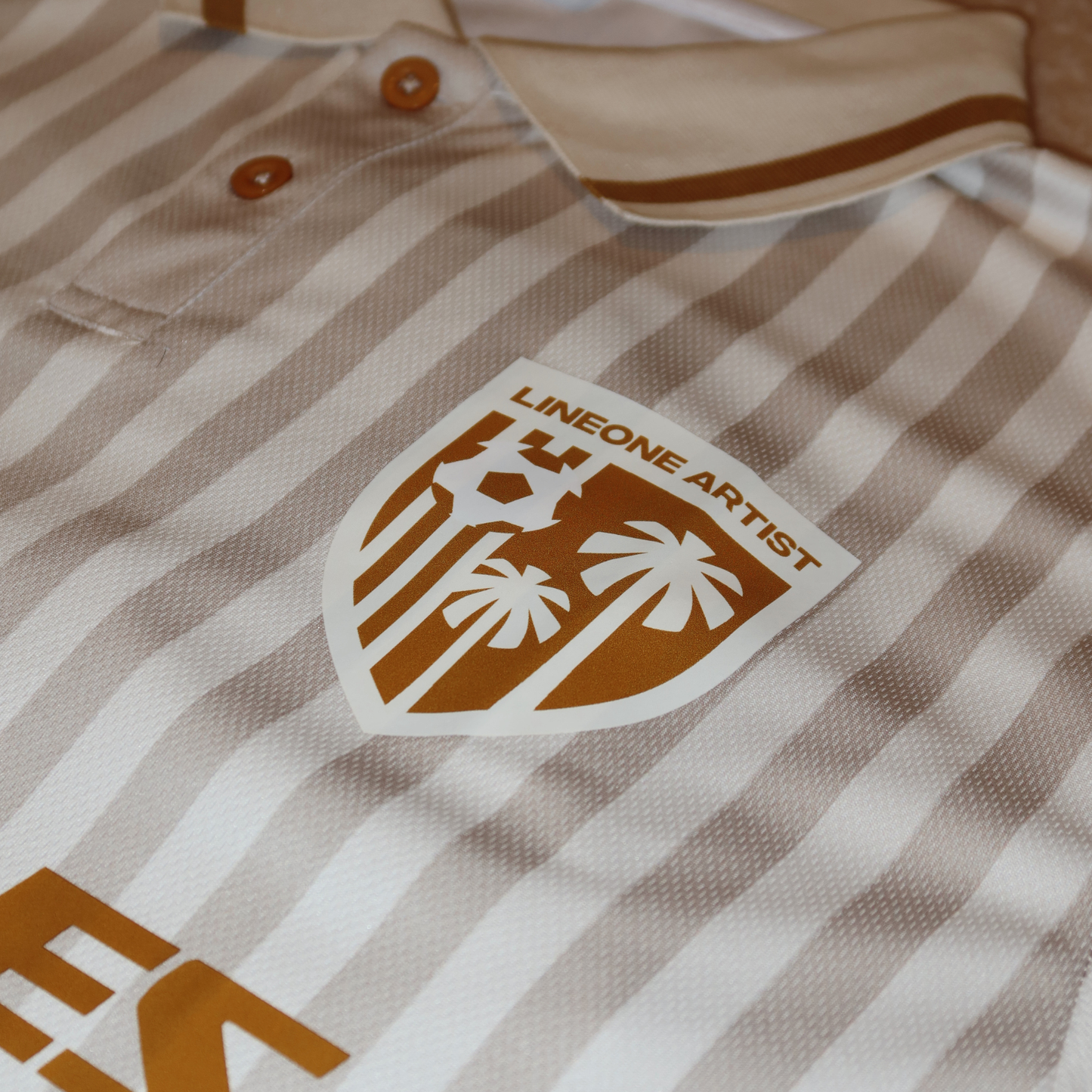 Close-up of LINEONE Hair Team Works Jersey cream away kit collar, button placket and gold crest patch