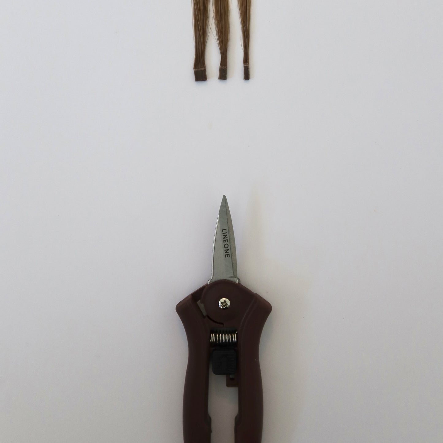 LINEONE Bond mini trimmer cutting hair weft strands on white background demonstrating trimmer functionality