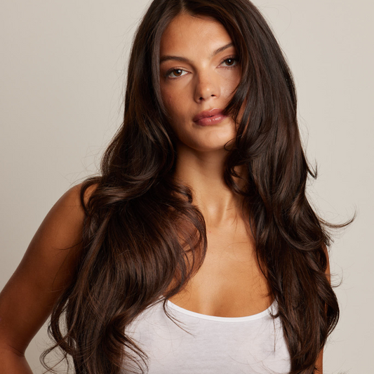 LINEONE Hair Brunette model wearing long, glossy chocolate Keratin Tip Straight extensions in a white tank against neutral