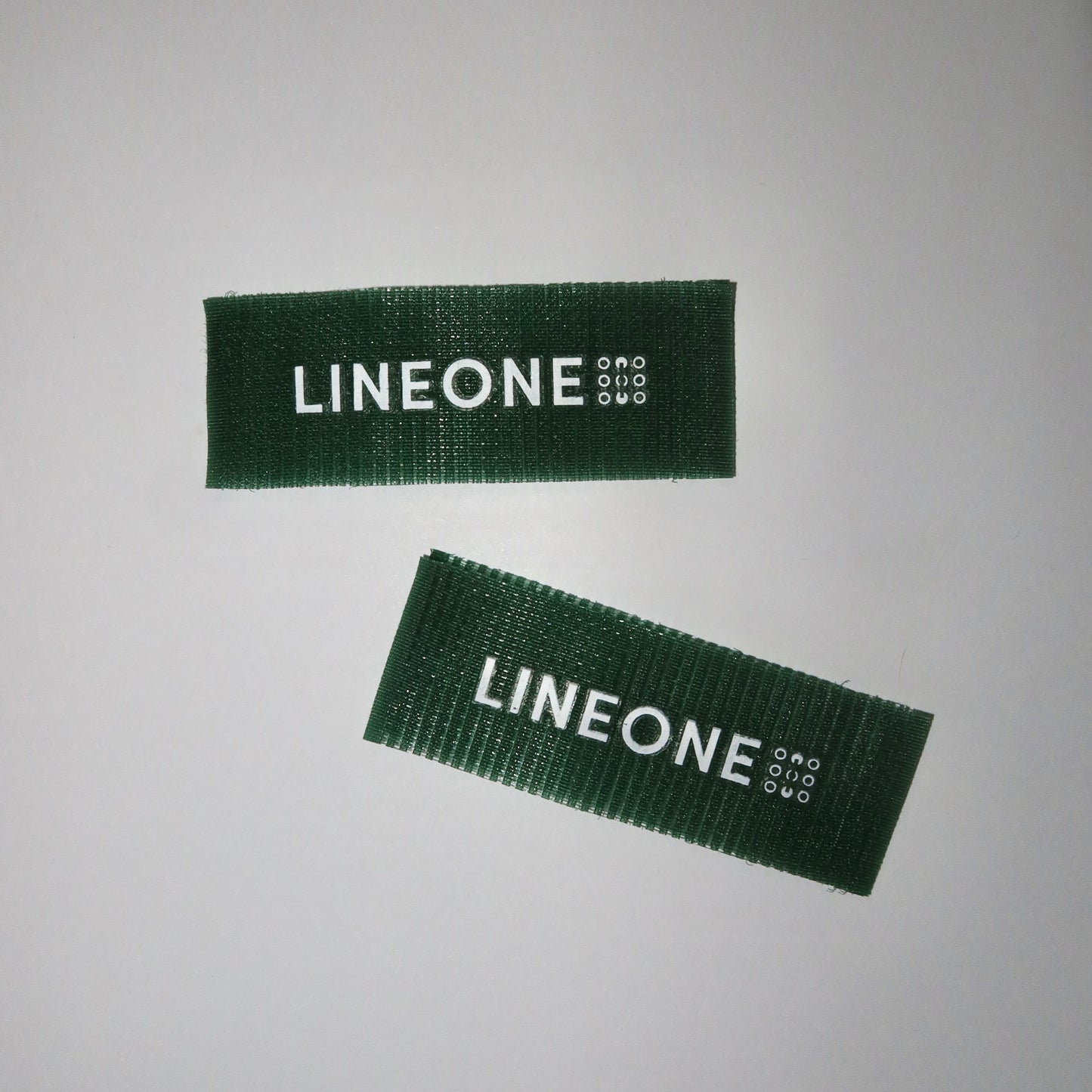 Two LINEONE Hair Grippers in hunter green velcro with white logo arranged at opposing angles