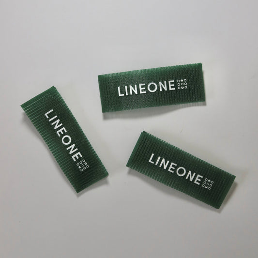 Three LINEONE Hair Grippers in hunter green velcro strips with white logo on white background