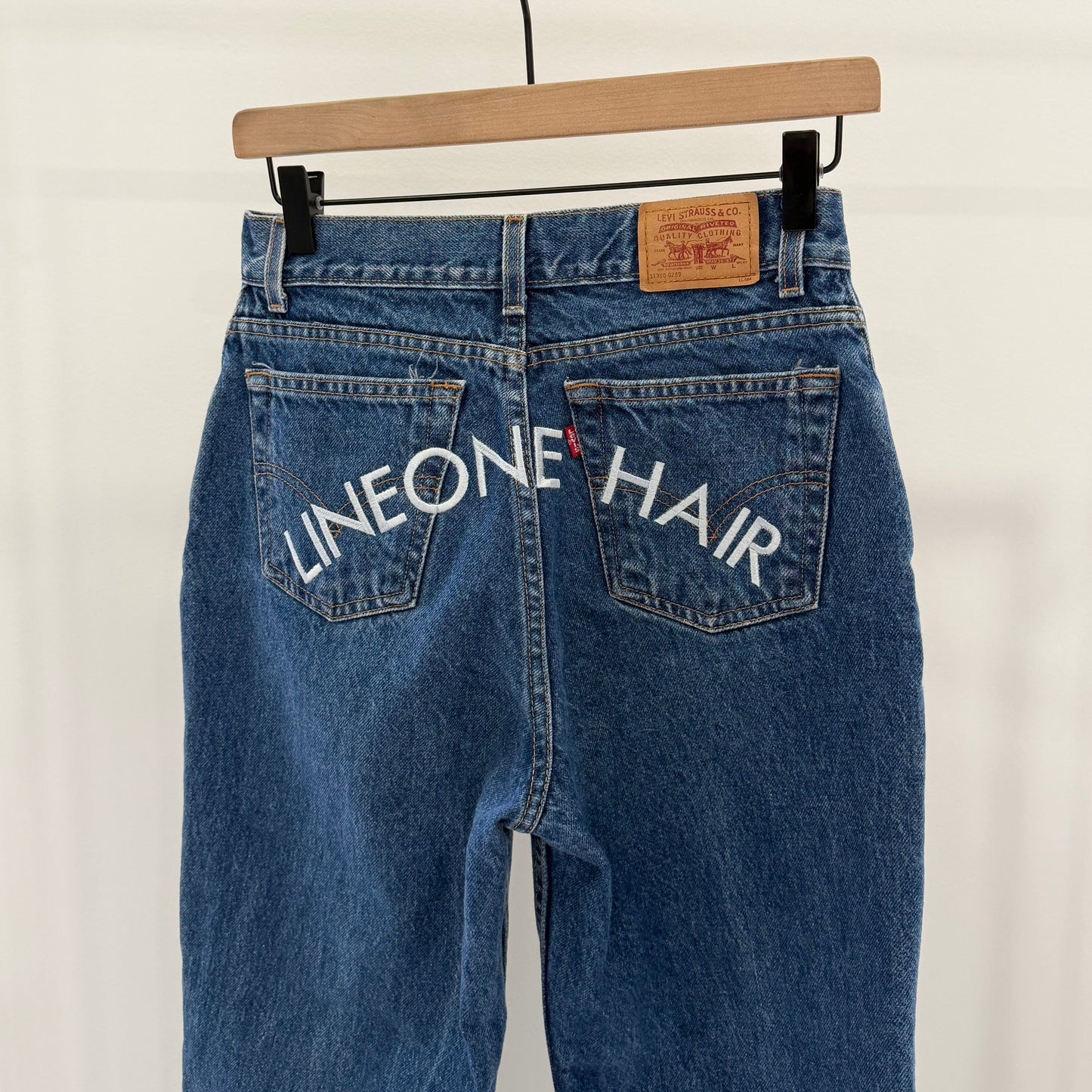 LINEONE Hair Jeans dark indigo back view on hanger with white LINEONE Hair pocket embroidery