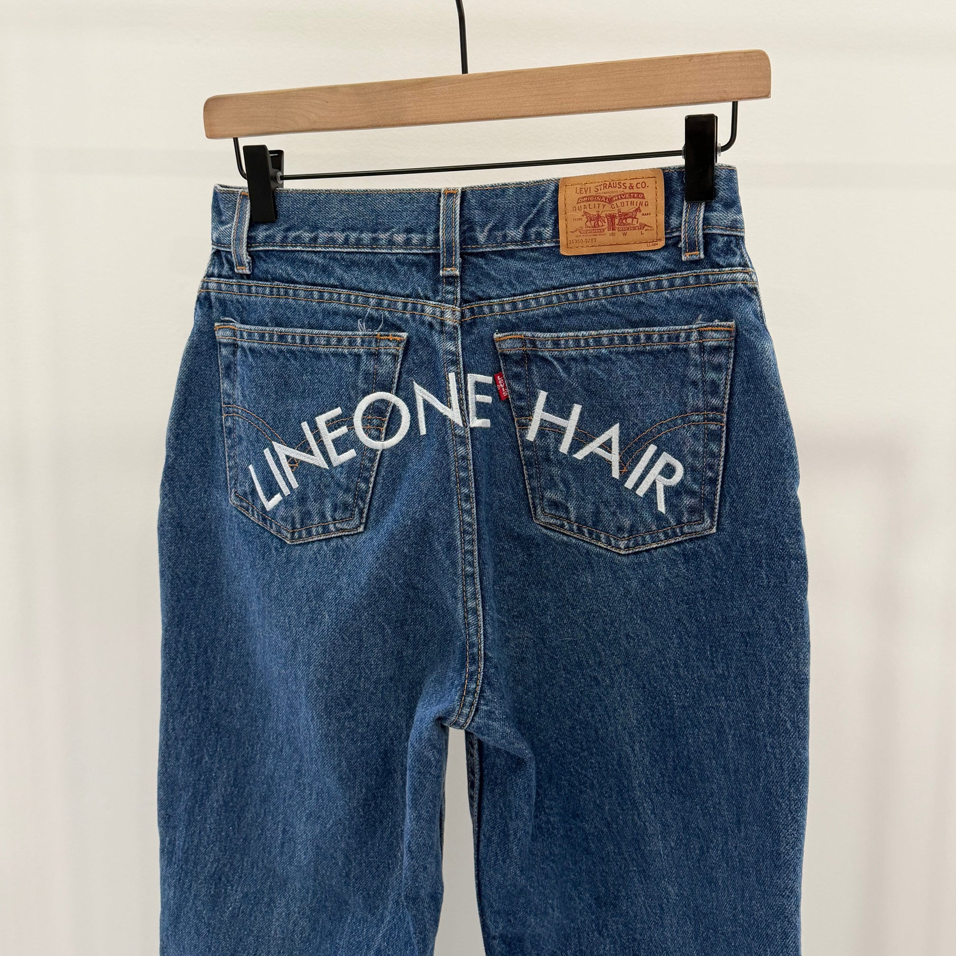 LINEONE Hair Jeans dark indigo back view on hanger with white LINEONE Hair pocket embroidery
