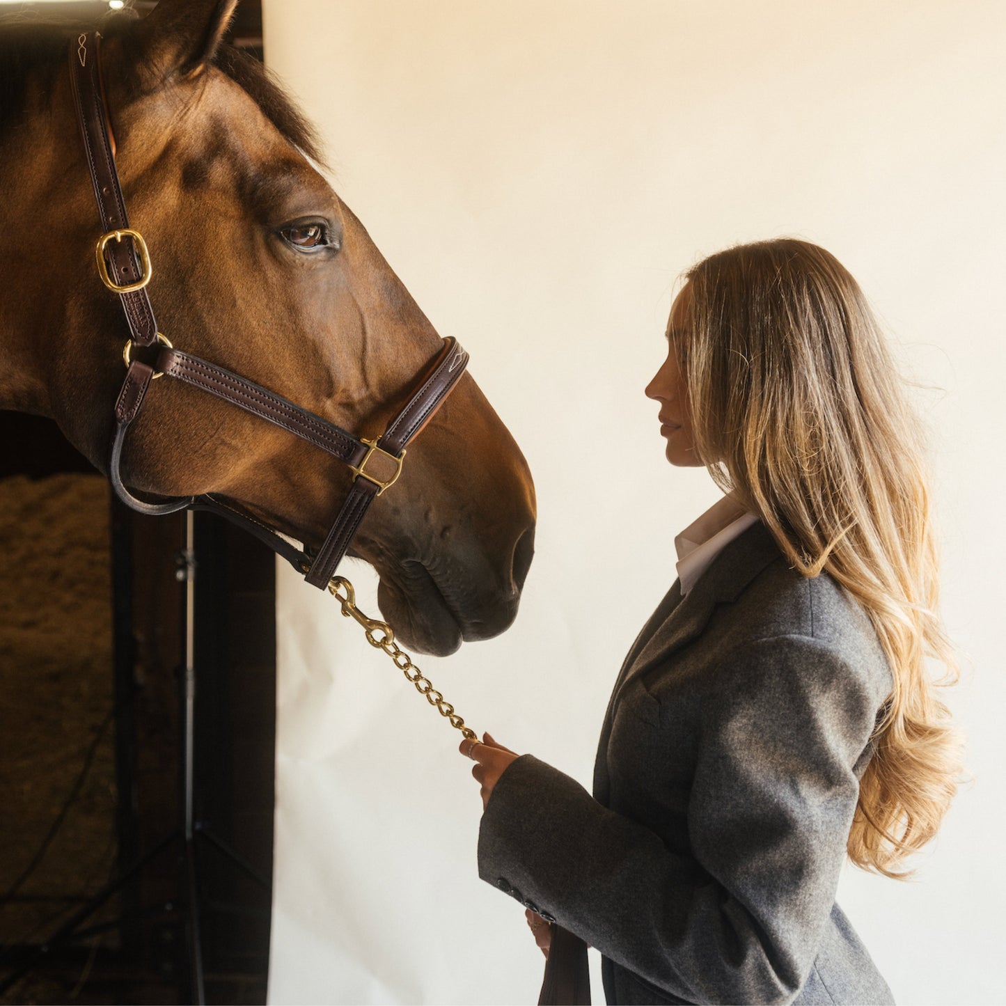 Blonde stylist in grey blazer leading a chestnut horse by the halter, LINEONE Hair Keratin Intro Kit Dimensional Brunette