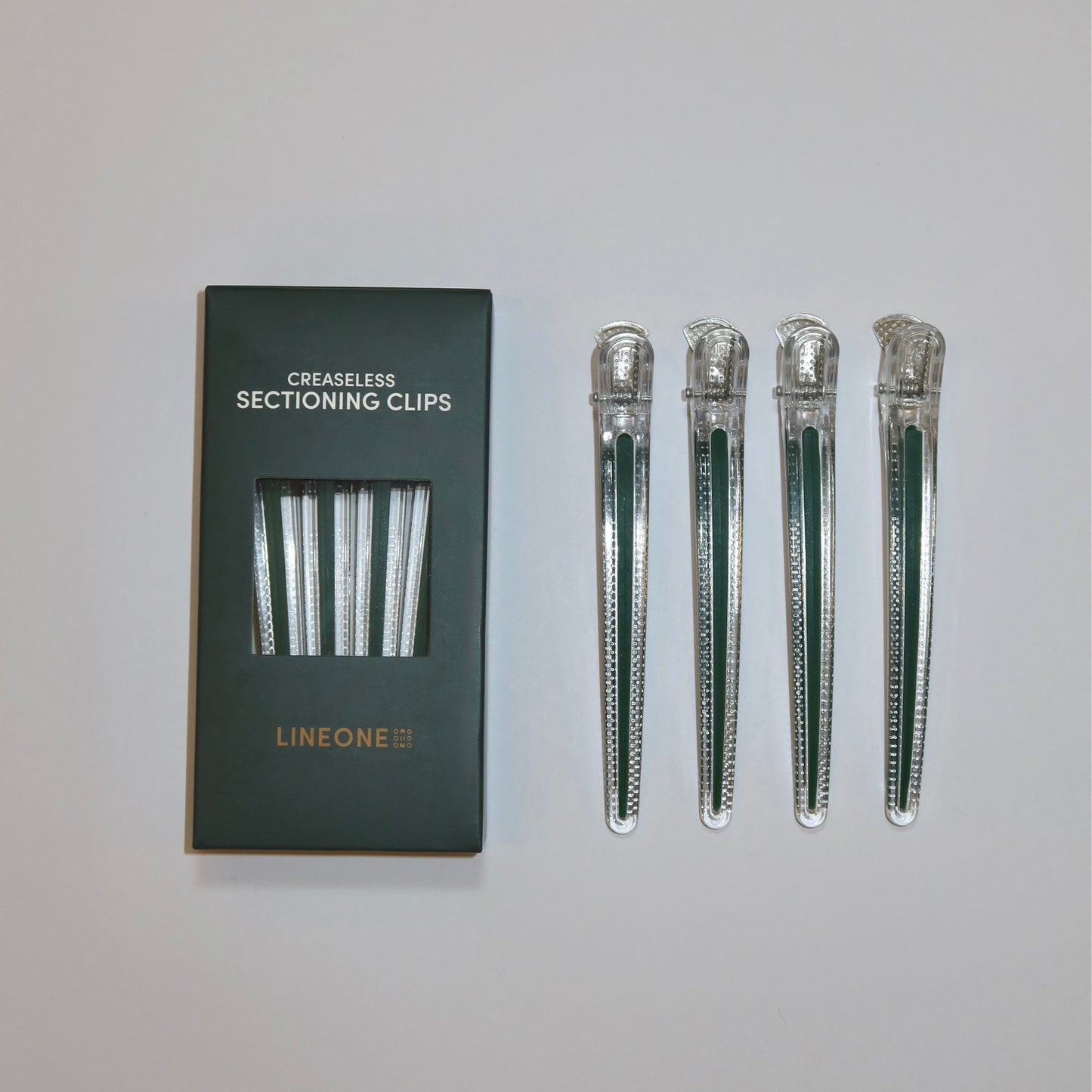LINEONE Hair Creaseless Sectioning Clips hunter green box beside four clear clips with green inserts