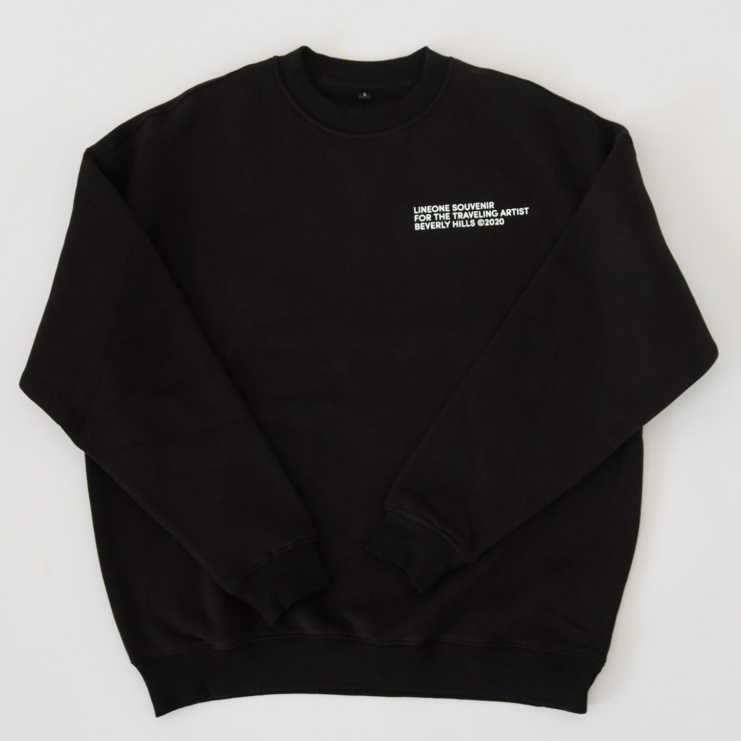 LINEONE Hair Pantone Crewneck in black laid flat showing white traveling artist chest print