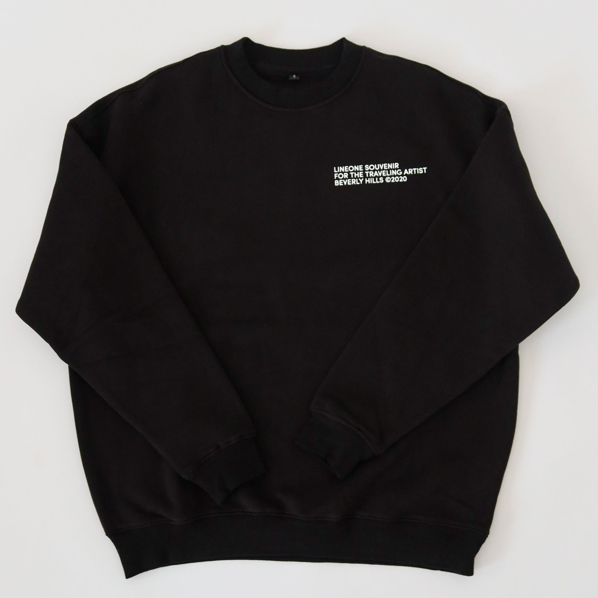 LINEONE Hair Pantone Crewneck in black laid flat showing white traveling artist chest print