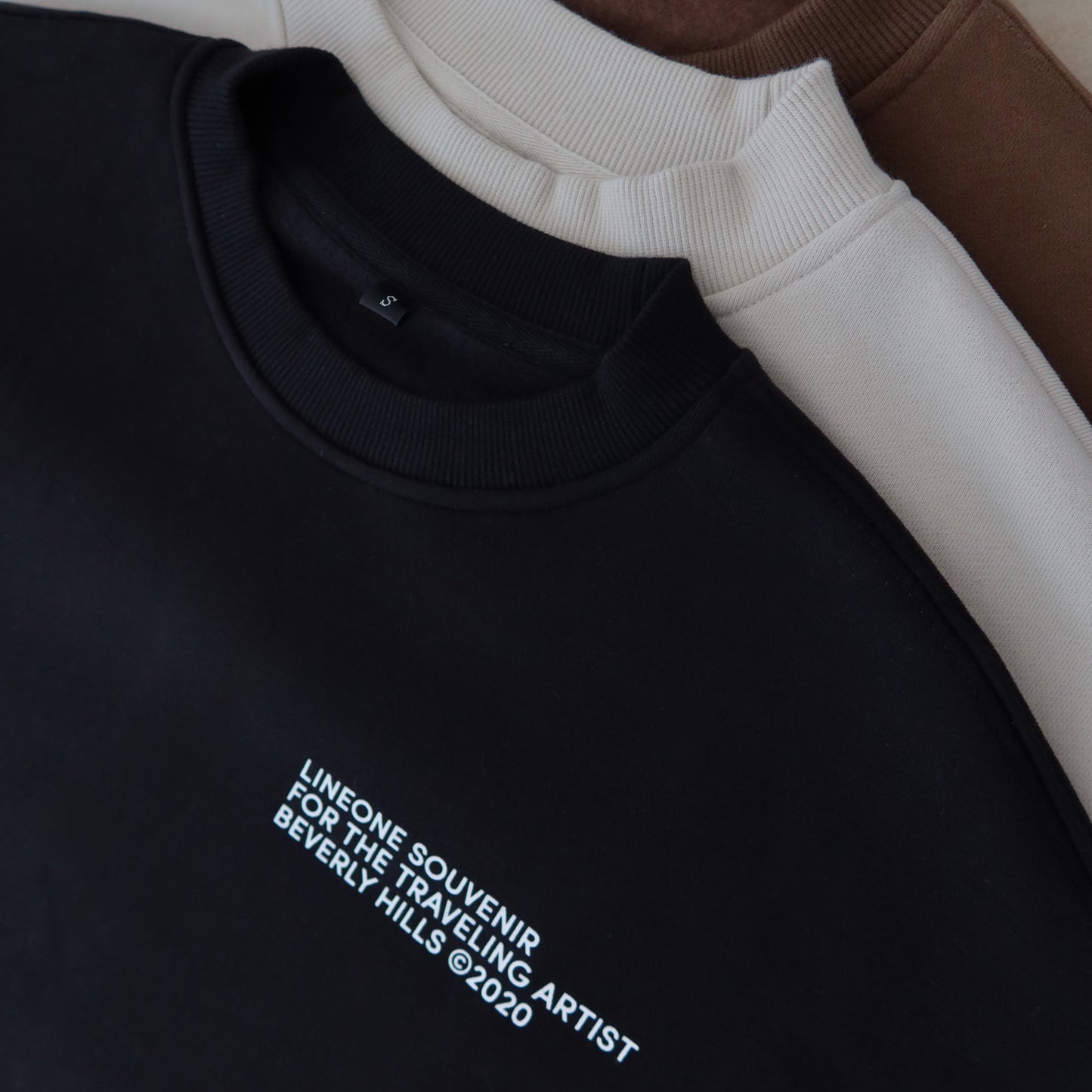 Black, cream and brown LINEONE Hair Pantone Crewnecks stacked at the neckline showing chest prints
