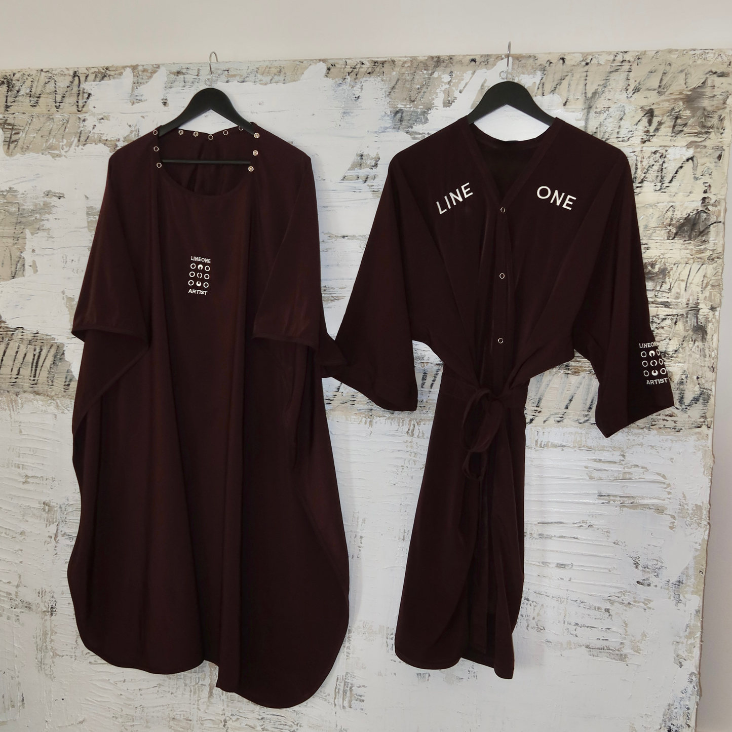 Two Coco-color LINEONE Hair Client Robes hung side by side on rustic painted board