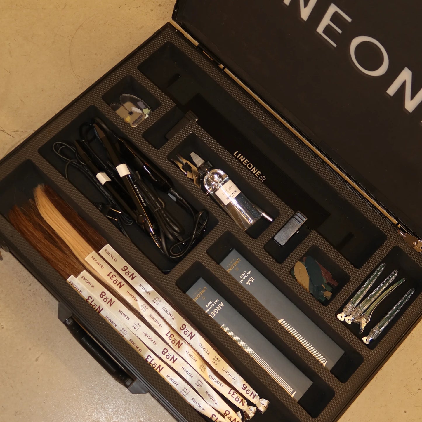 Open LINEONE Hair Briefcase showing organized keratin extension bundles, flat iron, tools, and stylist combs