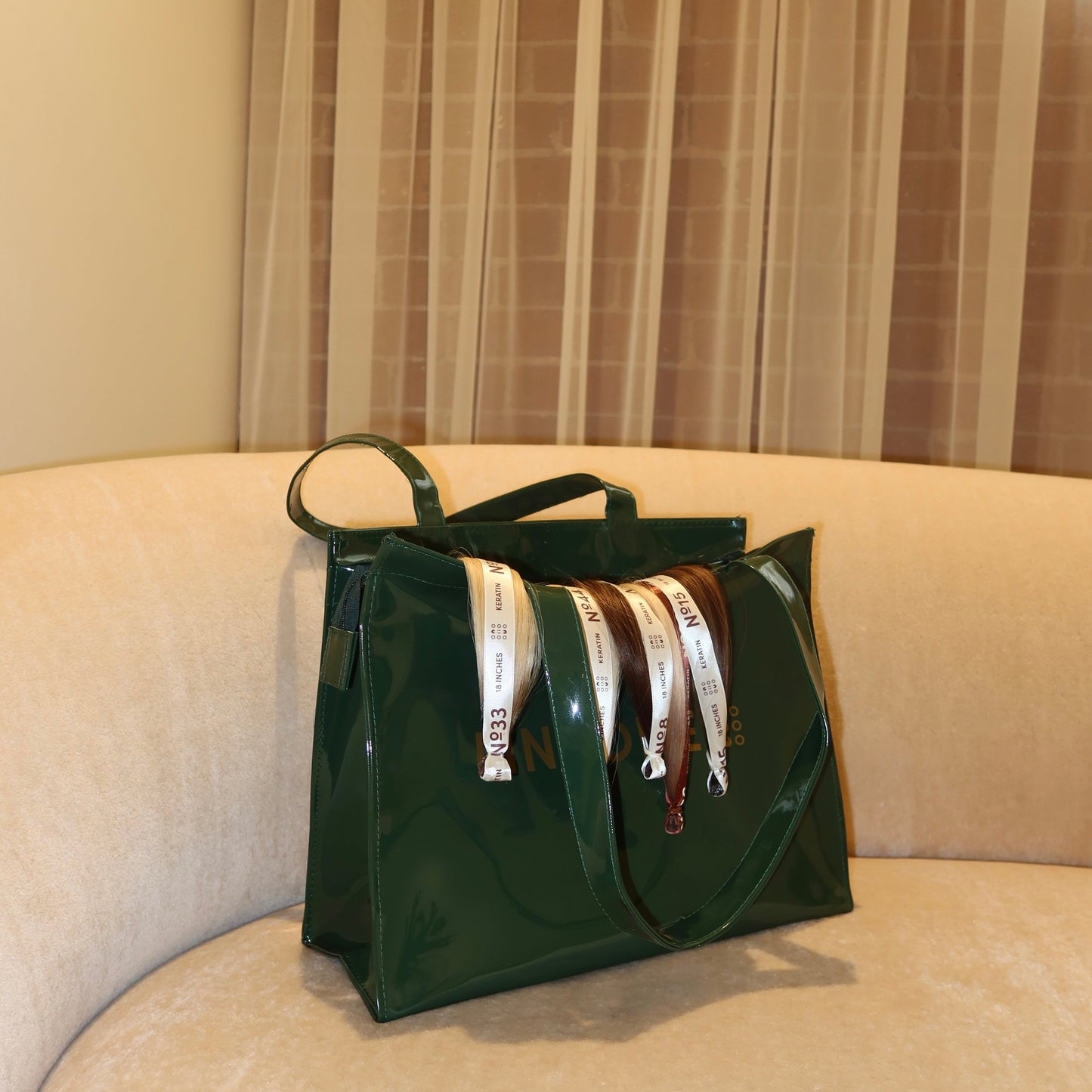 Side view of LINEONE Hair Rodeo Bag stuffed with rolled extension bundles on a beige curved sofa