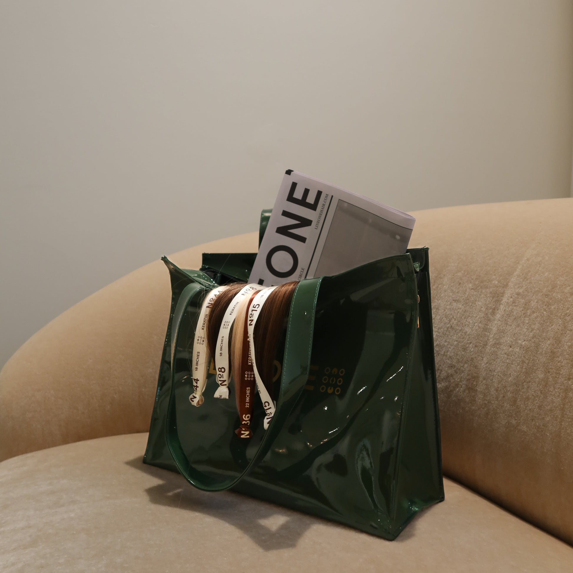 LINEONE Hair Rodeo Bag filled with numbered keratin extension bundles and newsprint on a beige sofa