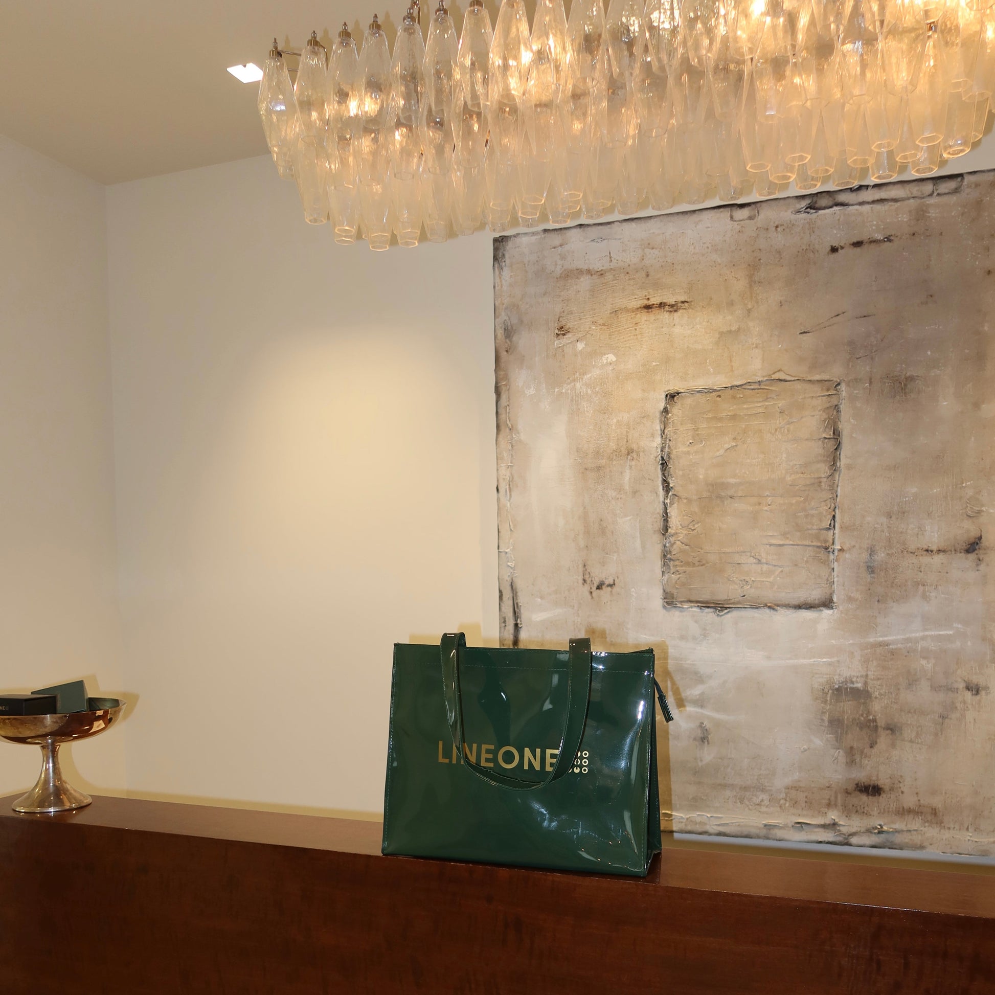 LINEONE Hair Rodeo Bag styled on a wood console under a glass chandelier with textured art behind