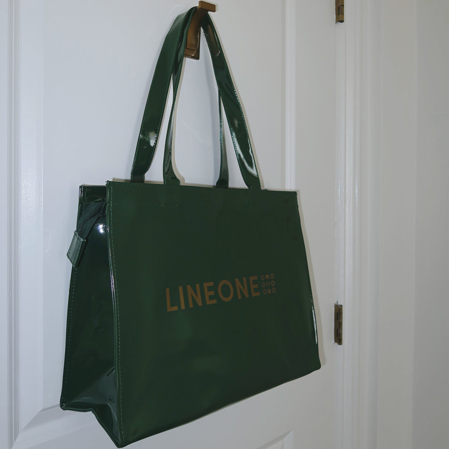 Hunter green LINEONE Hair Rodeo Bag hanging by its handles on a white panel door