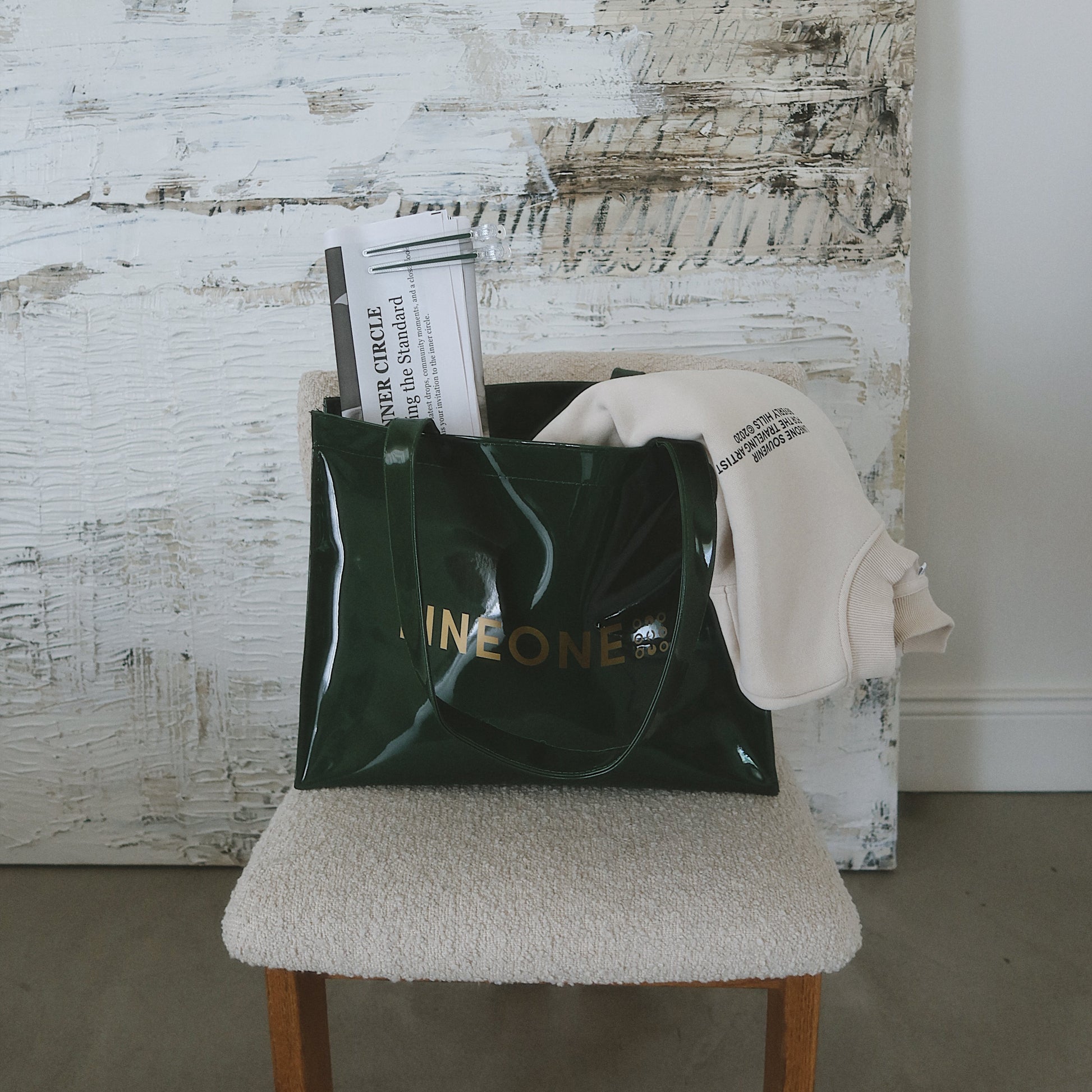 LINEONE Hair Rodeo Bag on a boucle stool with Newsprint and a folded ivory sweatshirt beside textured art